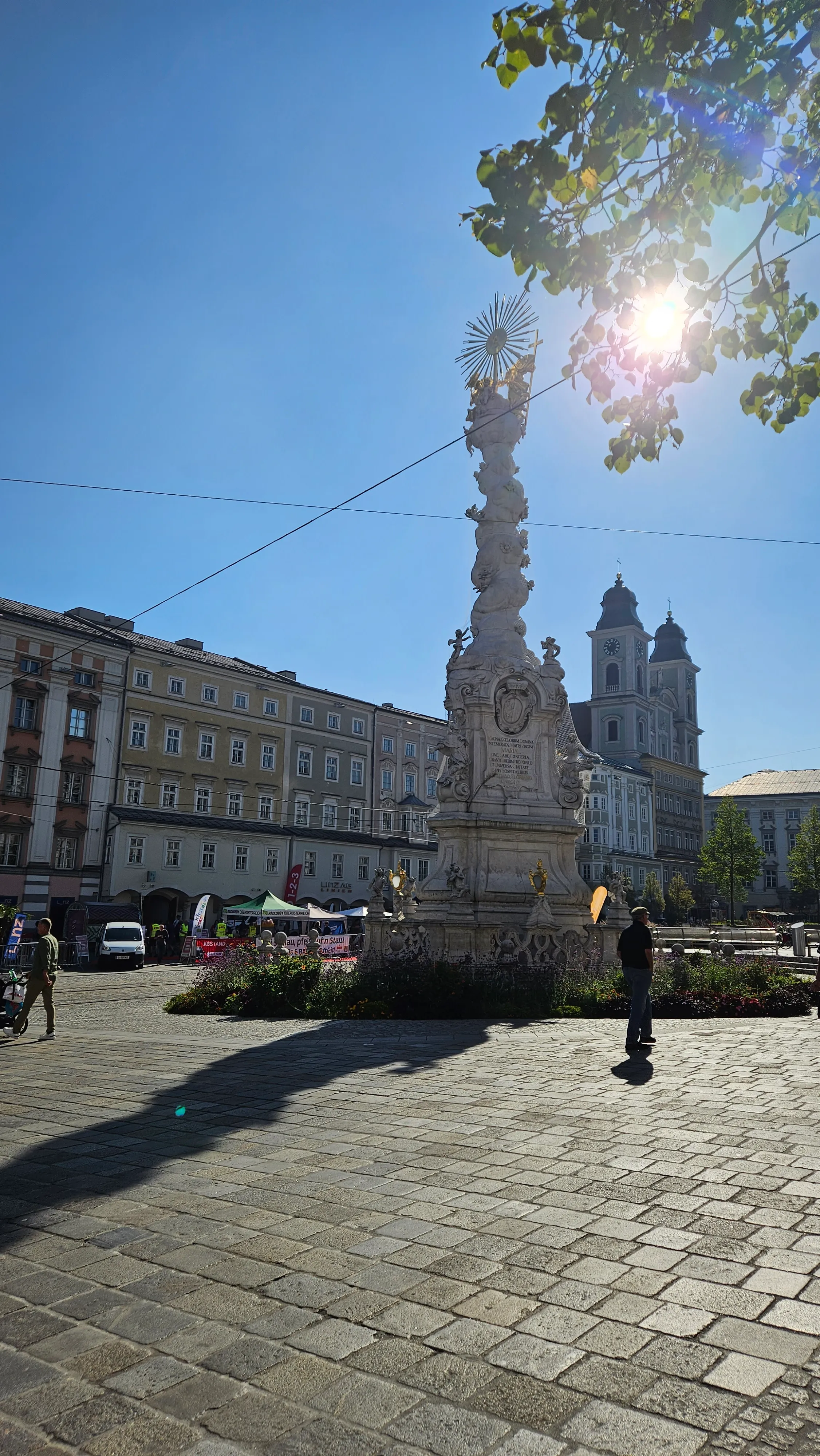 Linzer Hauptplatz mit Straßenbahn, Dreifaltigkeitssäule und Radfahrern