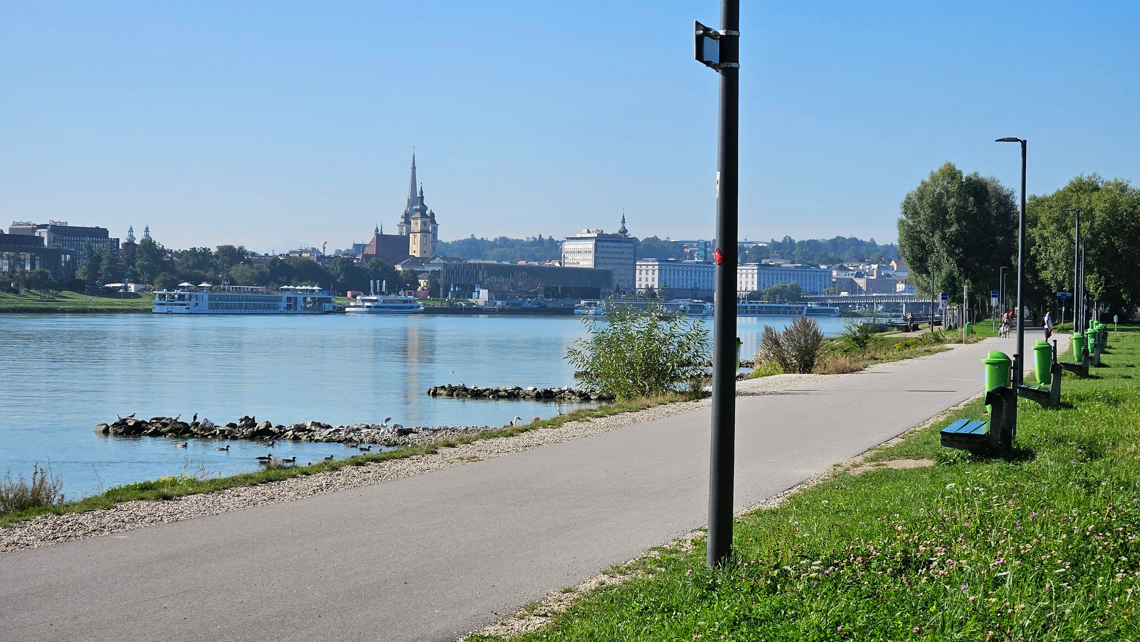 Blick über die Donau auf die Linzer Altstadt mit Türmen und Ausflugsschiffen